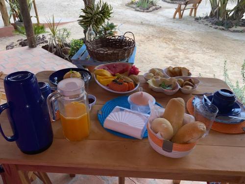 a table with breakfast foods and orange juice on it at Vilarejo Macapá Chalés in Luis Correia