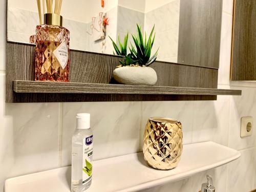 a bathroom shelf with a bottle of soap and a vase at Cottbus-Apartments - Apricot Apartment I privat I Wifi I Küche I Balkon in Cottbus