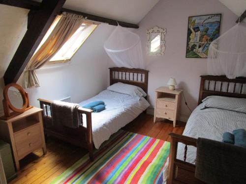 1 dormitorio con 2 camas individuales y alfombra de arco iris en Gîte du Vert Rivage à Stang Korvenn, en Laz