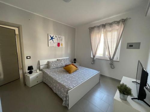 a white bedroom with a bed and a television at Sunrise Residence in Santa Domenica