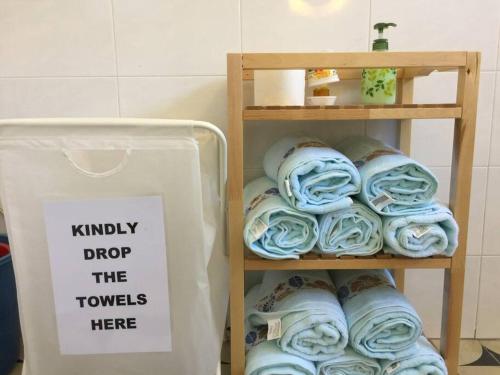 une étagère remplie de serviettes laminées bleues à côté d'un panneau dans l'établissement MELAKA BEACH VILLA ( A TYPE ), à Kelebang Besar