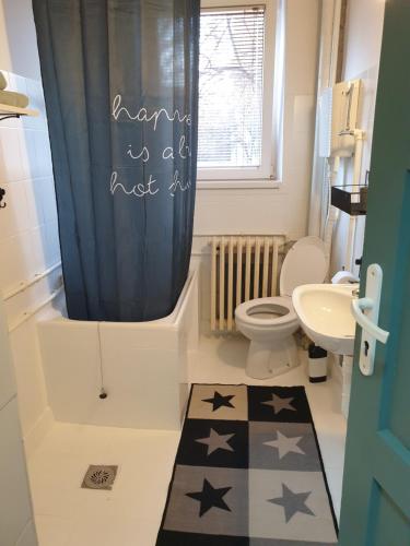 a bathroom with a toilet and a blue shower curtain at Apartman Park Jagodina-studio u centru grada in Jagodina