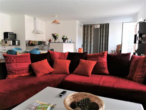 - un canapé rouge avec des oreillers rouges dans le salon dans l'établissement Le Moulin Jodet, à Notre-Dame-de-Monts