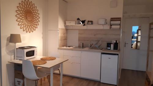 a small kitchen with a table and a microwave at Studio vue panoramique sur mer in Villers-sur-Mer