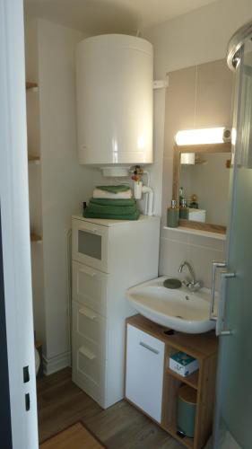 een badkamer met een witte wastafel en een spiegel bij Studio vue panoramique sur mer in Villers-sur-Mer