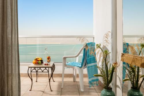 a chair and a table in a room with a window at Vert Dead Sea by AFI Hotels in Ein Bokek