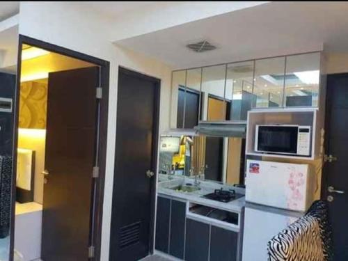 eine kleine Küche mit einem Kühlschrank und einer Mikrowelle in der Unterkunft Aliston Papilio Apartment in Ngawinan