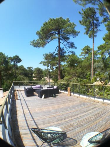 una terrazza in legno con divani e sedie. di Villa Paradis Pyla sur Mer a La Teste-de-Buch