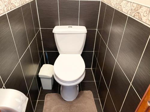a bathroom with a white toilet and black tiles at Apartment on Astana 12/1 in Ustʼ-Kamenogorsk