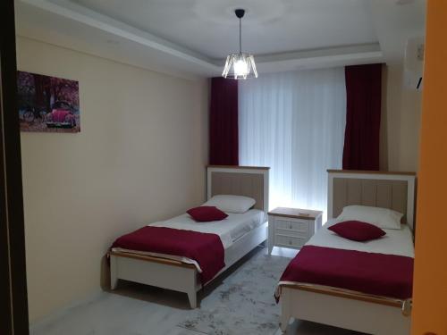 two beds in a room with red curtains at Canan Residance in Demre