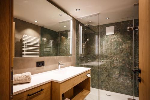 La salle de bains est pourvue d'un lavabo et d'une douche. dans l'établissement Pension Bergheim, à Reith im Alpbachtal