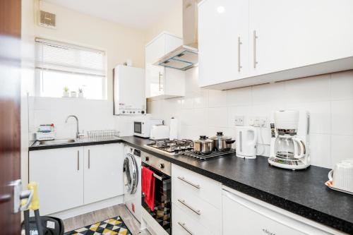 a kitchen with white cabinets and black counter tops at MPL Apartments - Malden Road Serviced Accommodation in Watford