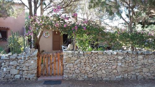 una casa con un muro di pietra e un cancello con fiori di Villa Chiara Villetta con giardino IUN 4807 a Porto Pollo