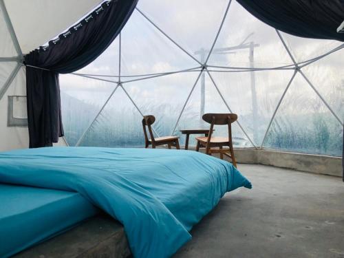 ein Schlafzimmer mit einem Bett und zwei Stühlen in einem Zelt in der Unterkunft Kubah Bali Glamping in Kintamani