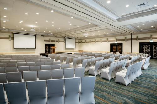an empty lecture hall with white chairs and screens at Vert Dead Sea by AFI Hotels in Ein Bokek