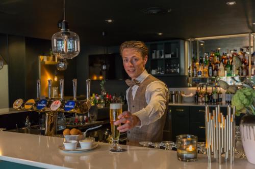 a man standing behind a bar preparing a drink at Van der Valk Hotel Volendam in Volendam