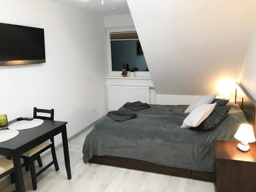 1 dormitorio con cama, mesa y TV en Apartamentai Nidos centre Taikos g, en Nida