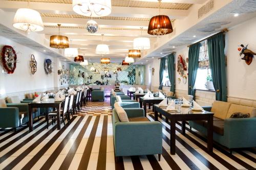 un restaurante con mesas, sillas y lámparas de araña en Nabat Palace Domodedovo, en Voyevodino