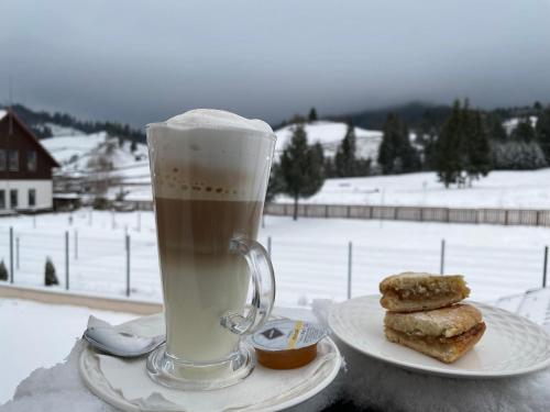 a cup of coffee next to a plate of cookies at Pensiunea Maria in Colibiţa
