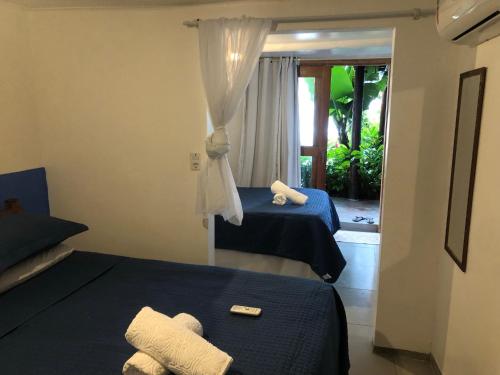 a hotel room with two beds and a window at Pousada Pipe House in Itacaré
