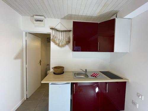a kitchen with red cabinets and a sink at Studio entre lac et océan à Hossegor in Soorts-Hossegor