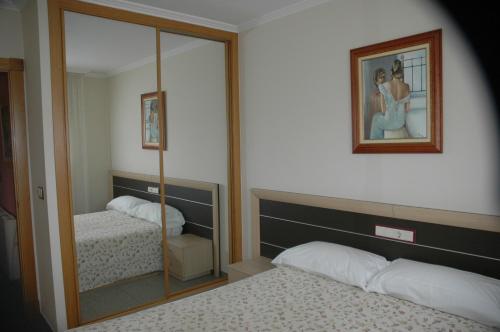 1 dormitorio con 2 camas y espejo en Apartamentos Turisticos Vilagarcía- Rio Ulla, en Vilagarcía de Arousa