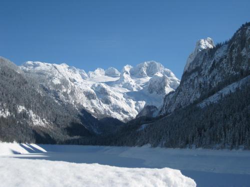 a snow covered mountain with a lake in the foreground at Appartement Alpenblick in Gosau