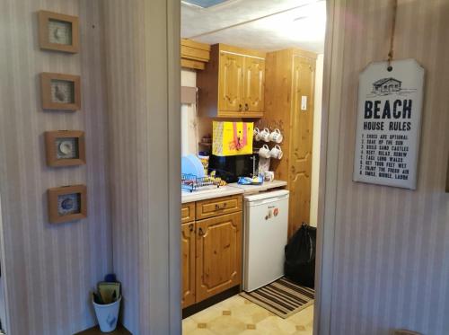 uma cozinha com armários de madeira e um frigorífico branco em Heacham South Beach static caravan em Heacham