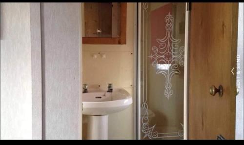 a bathroom with a white sink and a mirror at Heacham South Beach static caravan in Heacham