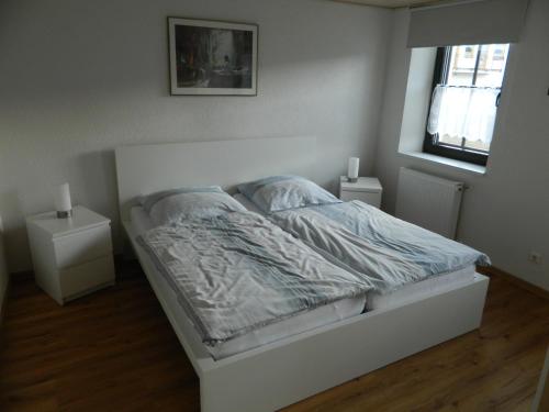 Ferienwohnung Bretz في Dreis: سرير ابيض في غرفة نوم مع مواقف ليلتين