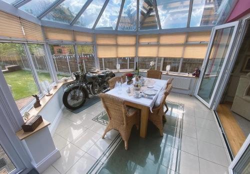a dining room with a table and a motorcycle in a conservatory at Keppel Gate B&B - Silver Birch Ensuite Room in Overseal