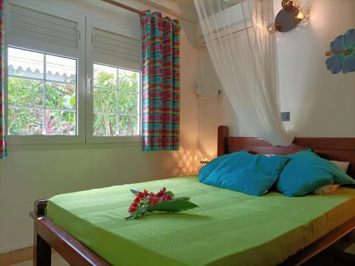 a bedroom with a green bed with flowers on it at le colibri ble in Sainte-Anne