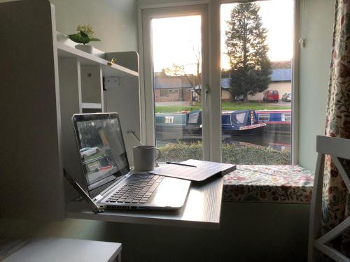 einen Laptop auf einem Schreibtisch neben einem Fenster in der Unterkunft Marina View cottage in Furness Vale