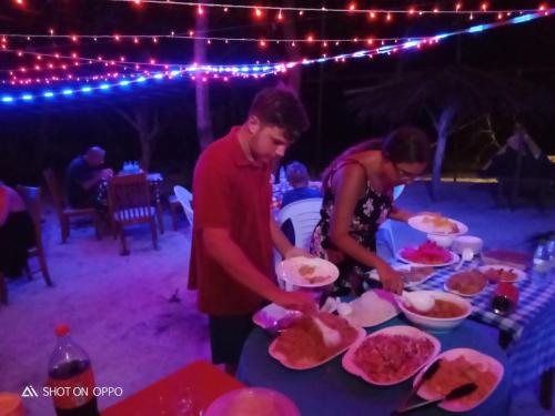a man and a woman preparing food on a table at Malas Island View in Fulidhoo
