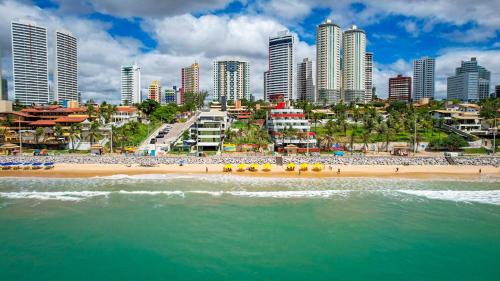 a beach in front of a city with tall buildings at Kings Flat - Apartamentos com conforto beira mar in Natal