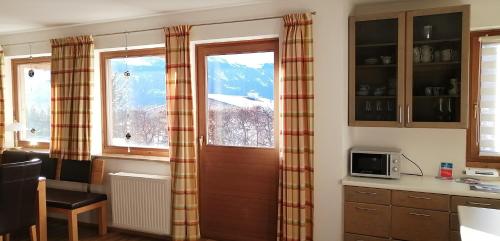 a kitchen with a wooden door and two windows at Haus Jessica incl National Park Sommercard in Mittersill