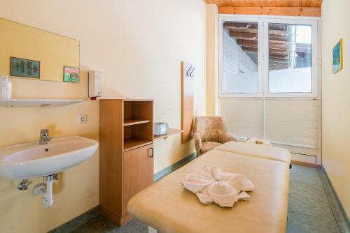 un baño con lavabo y una mesa con una flor. en Ferienhotel Knollhof, en Ramsau am Dachstein