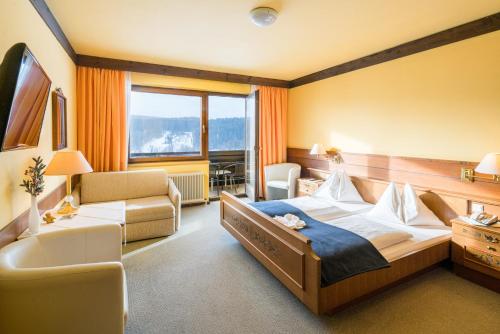 a hotel room with a large bed and a chair at Ferienhotel Knollhof in Ramsau am Dachstein