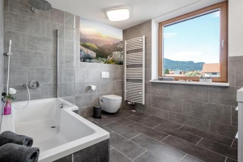 a bathroom with a white tub and a window at Ferienwohnung zum Traumblick in Pfronten