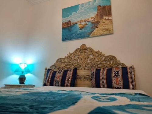 a bedroom with a bed with a painting on the wall at Dar El Kasba Riad Guest House in Bizerte