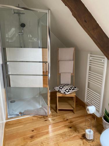 a bathroom with a glass shower and a chair at La Vieille Boulangerie in Langourla