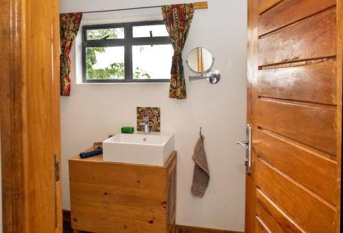 a bathroom with a sink and a wooden door at Isunga Lodge in Kibale Forest National Park