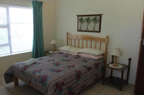 een slaapkamer met een bed, 2 lampen en een raam bij Tulip Close in Stilbaai