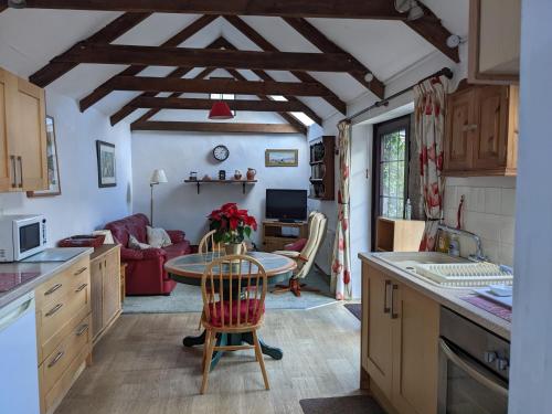 a kitchen with a table and a living room at The Cottage, Little Trembroath in Stithians