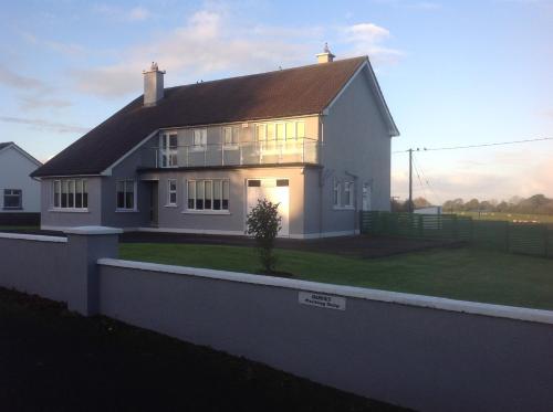 a white house with the sun shining on it at Lilac Manor in Sligo