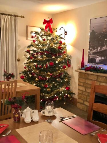 a christmas tree in a dining room with a table at Cornerways B&B in Chipping Campden