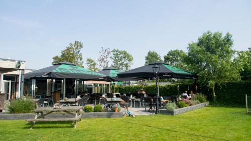 a patio with tables and chairs and umbrellas at Chaletparc Krabbenkreek Zeeland - Chalet 84 in Sint Annaland