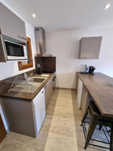 une cuisine avec des placards blancs et un comptoir en bois dans l'établissement Maison + jardin vue sur les montagnes, à Barcelonnette