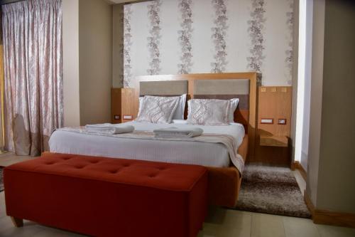 a bedroom with a large bed and a red bench at New W Hotel in Tirana