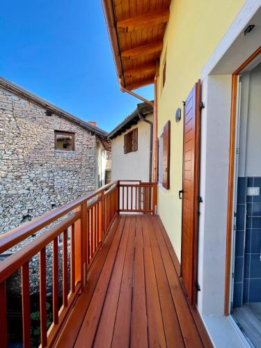 a balcony with a wooden deck with a stone wall at Appartamenti Le Tre Rose in Nago-Torbole